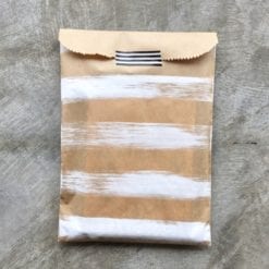 brown kraft paper bag painted with white stripes and sealed with black & white striped washi tape