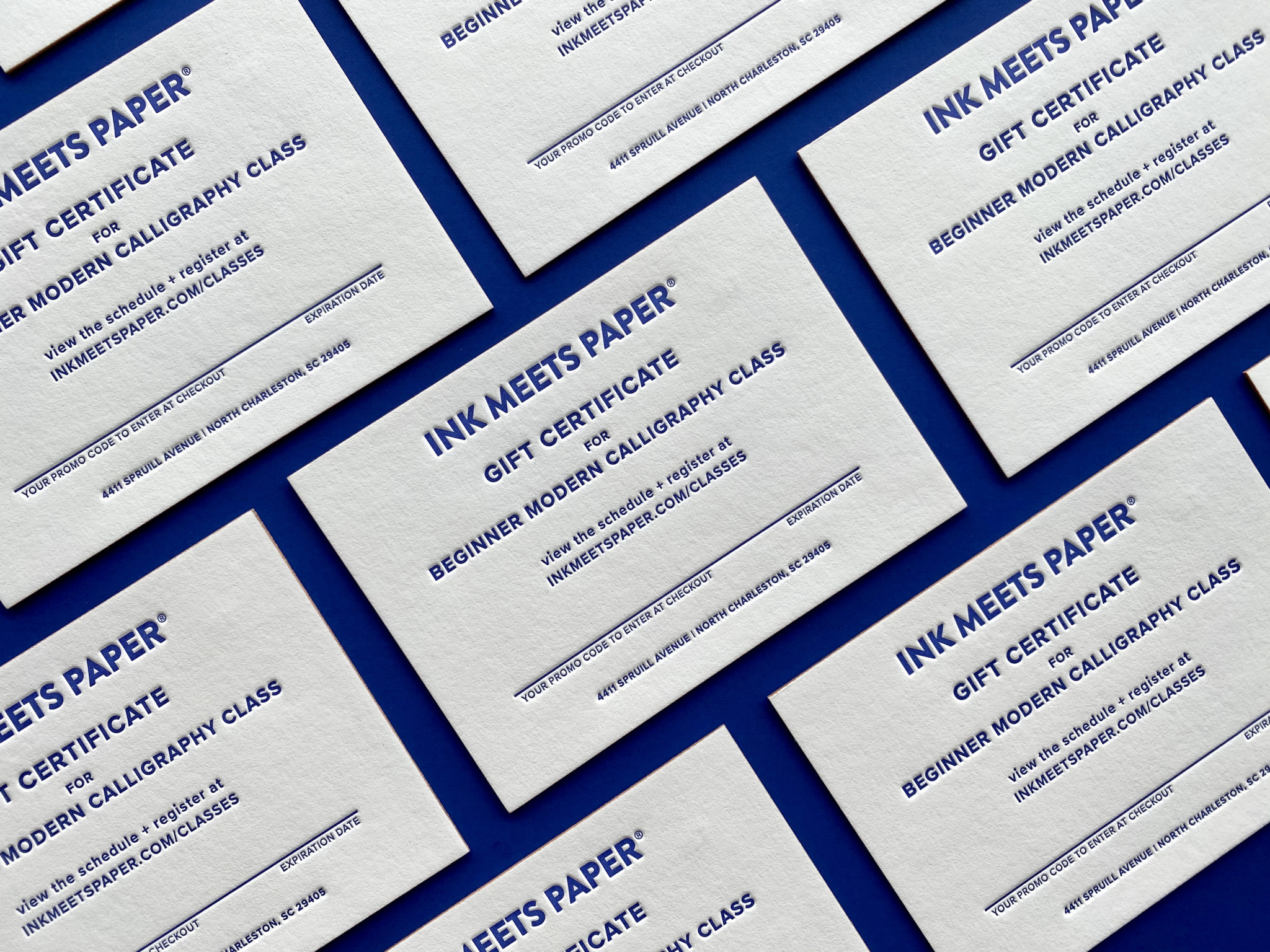 Letterpress-printed Gift Certificates laid out in a diagonal grid on a cobalt blue background.