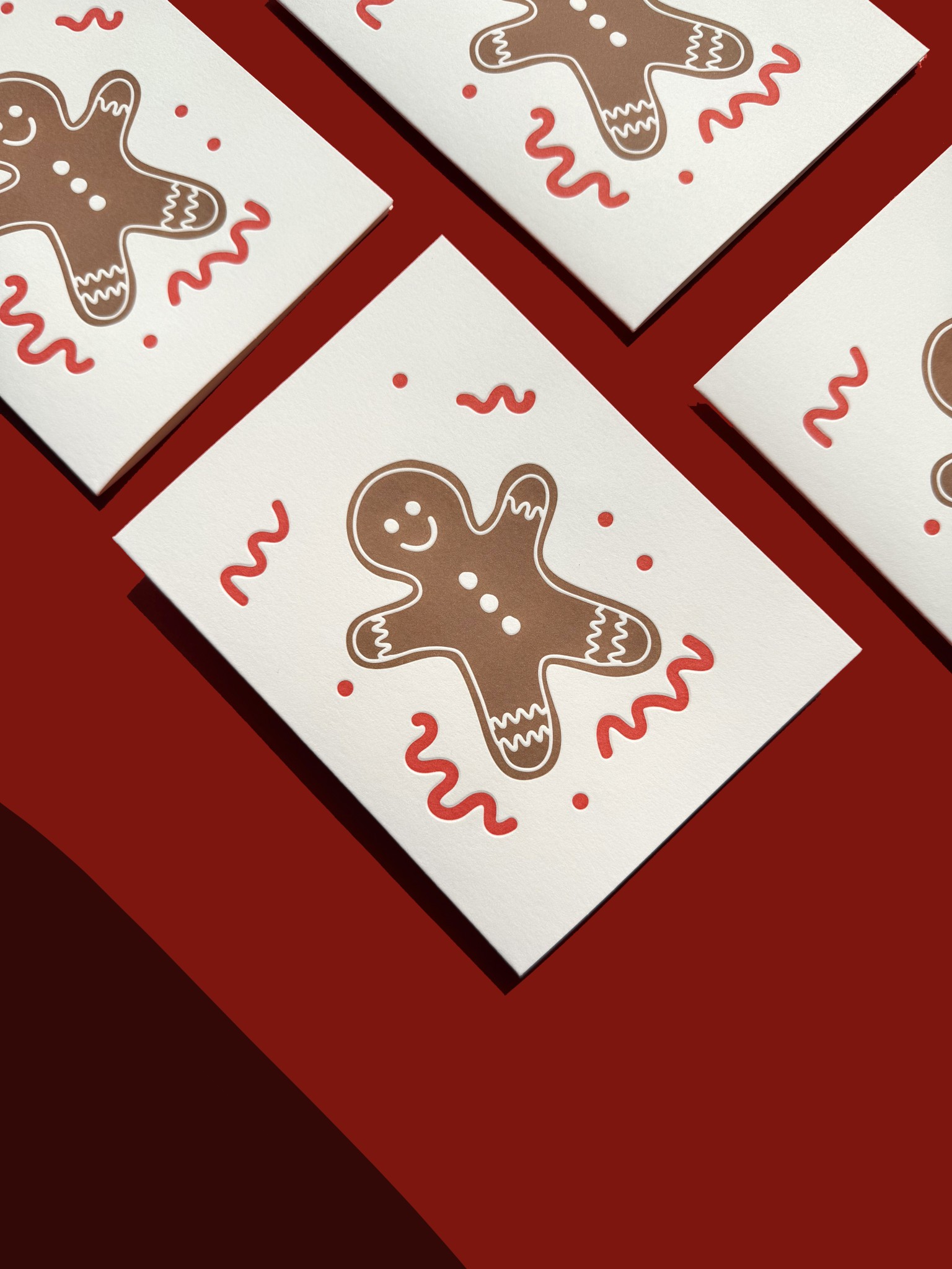 Gingerbread Friend boxed Christmas cards fanned on a red surface